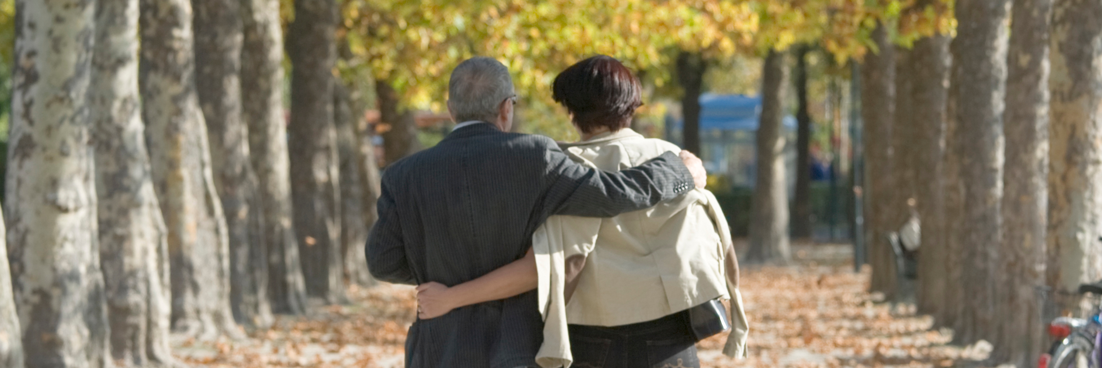 Husband and wife walking with hands around each others backs