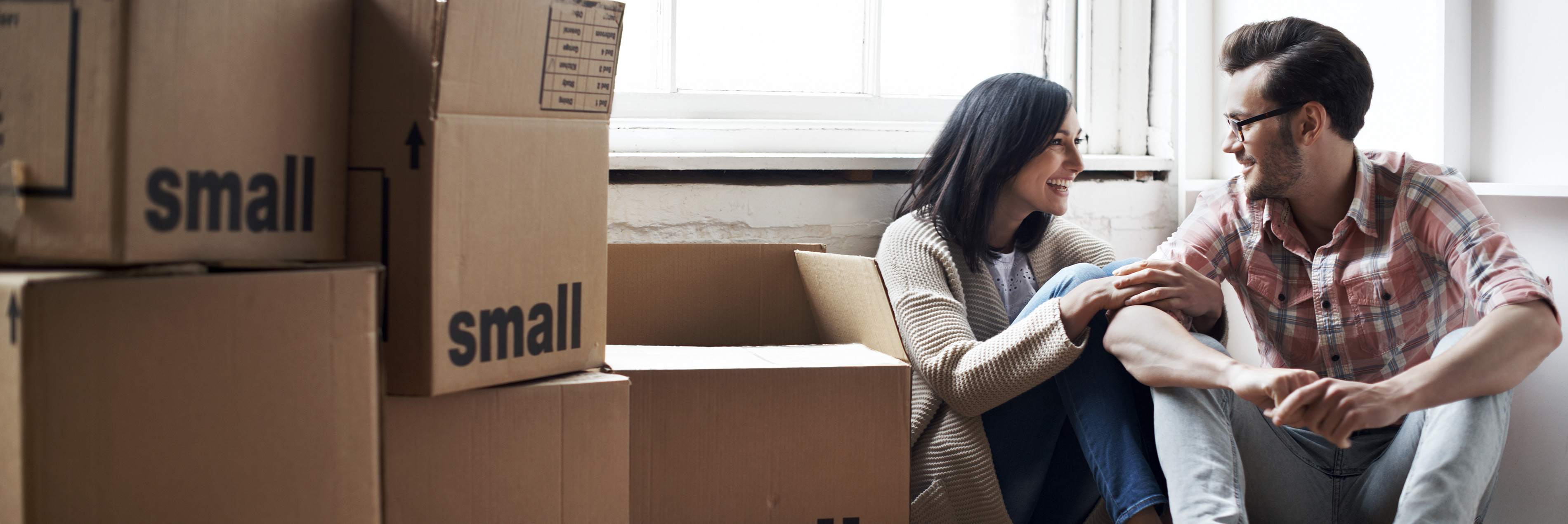 Couple sitting on floor surrounded by moving boxes