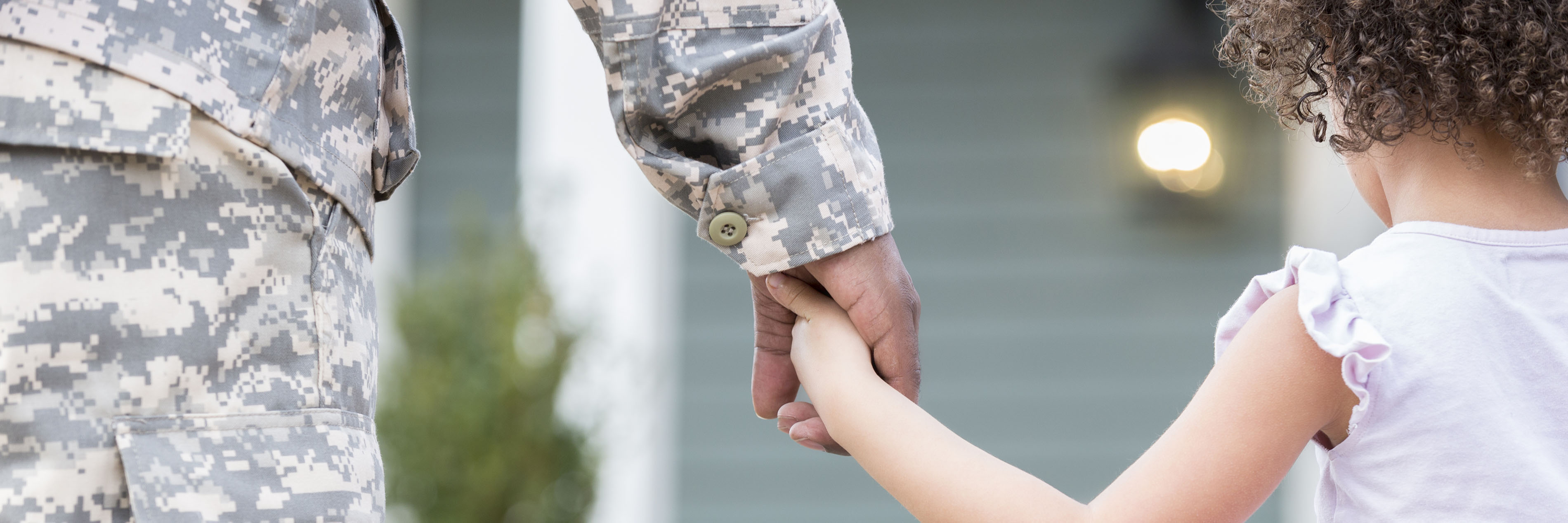 Girl holding military father's hand