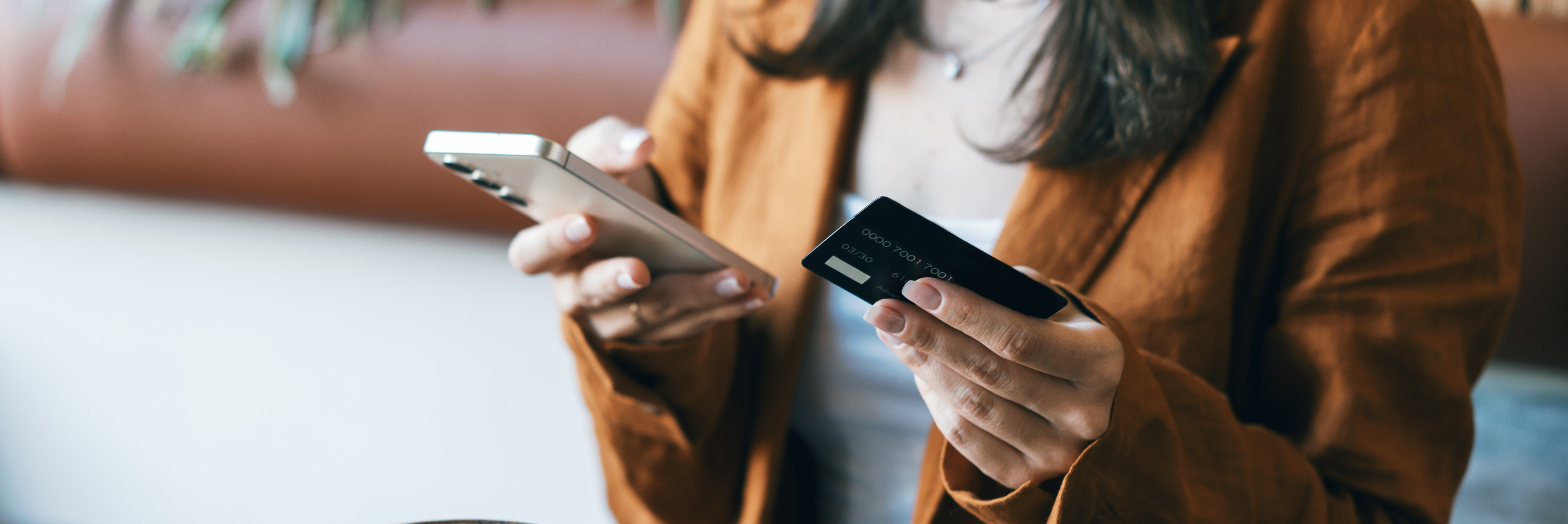 Person holding credit card in one hand and mobile phone in the other