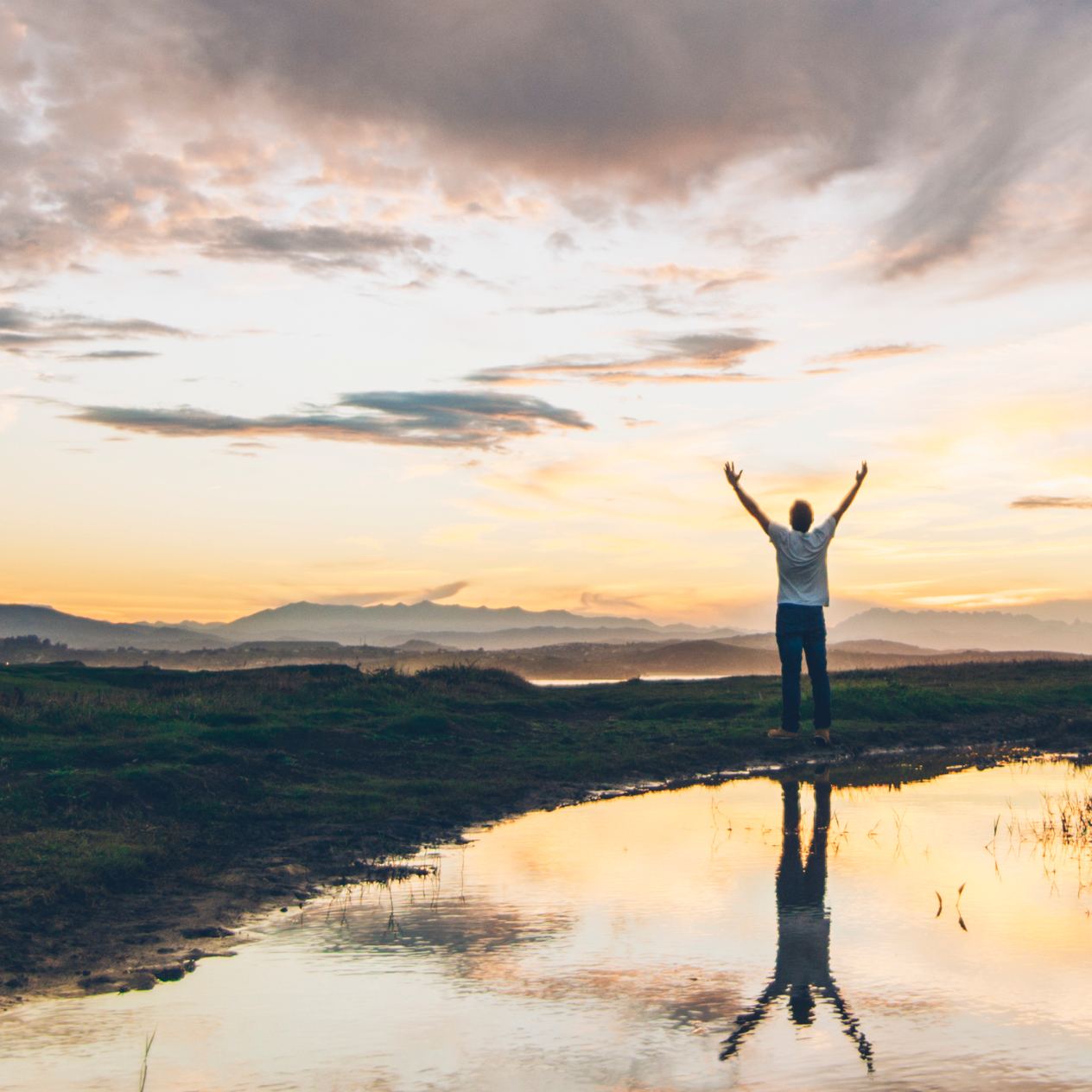 Man with arms up facing dawn